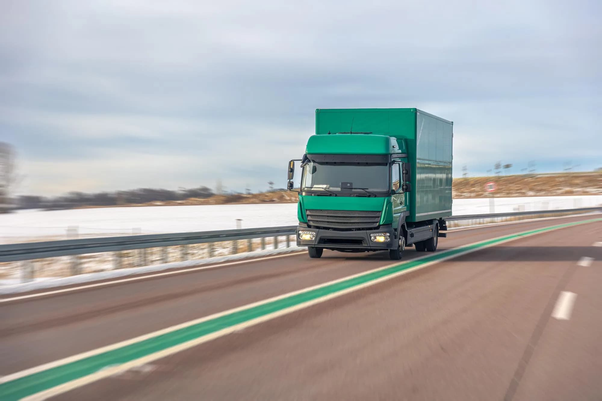 A lorry running along an open road, the roadside blurred by its speed